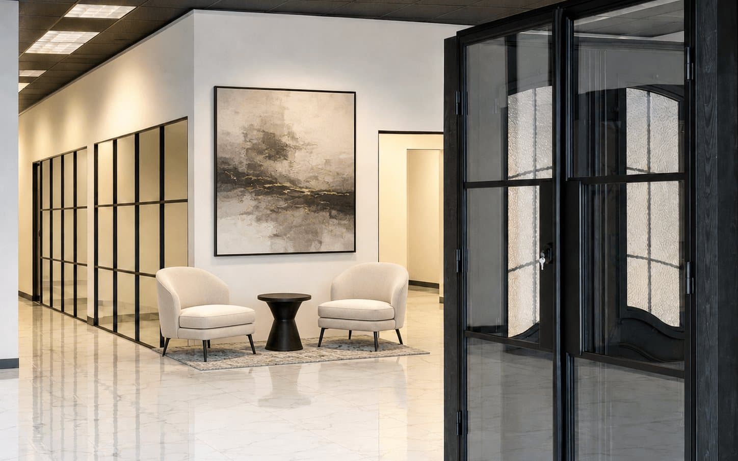 A seating area in the Brandon showroom with two upholstered chairs in front of black steel-framed glass partitions and a decorative iron door.