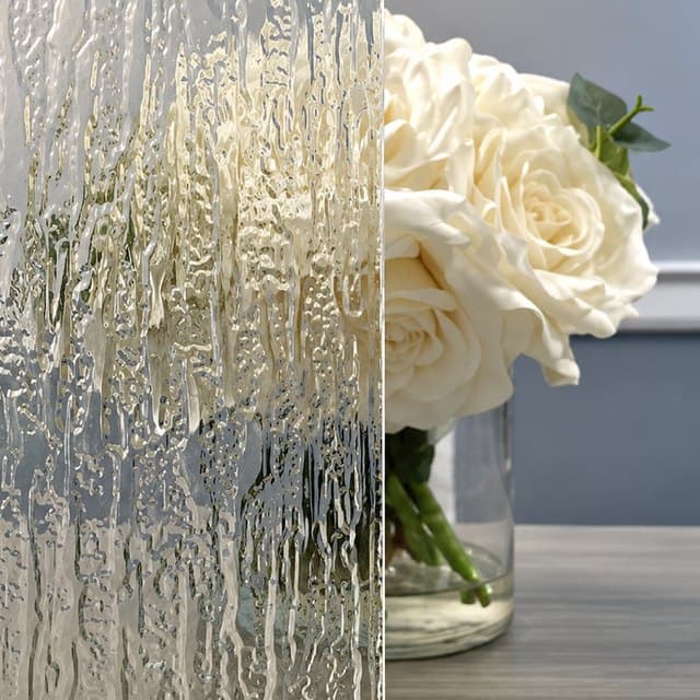 Textured rain glass beside clear glass, showing how much each one obscures a vase of white roses behind it.